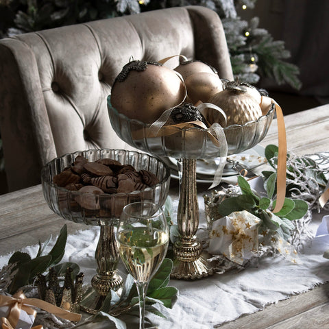 Fluted display bowls with gold balls on a wooden table.