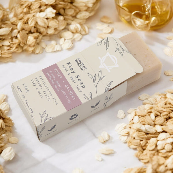 Klay Soap - Honey Oatmeal. A rectangular bar of natural, light-coloured soap with visible oatmeal flakes for gentle exfoliation. The soap is infused with Kaolin clay for oil control and has a comforting honey and oatmeal scent.