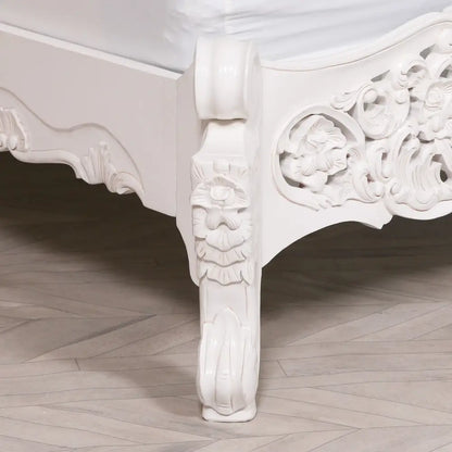 Ornate white furniture leg showcasing intricate scrollwork on a French style Rococo bed