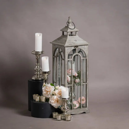 Ornate metal lantern with glass sides, flowers, and candles in a wooden lantern set