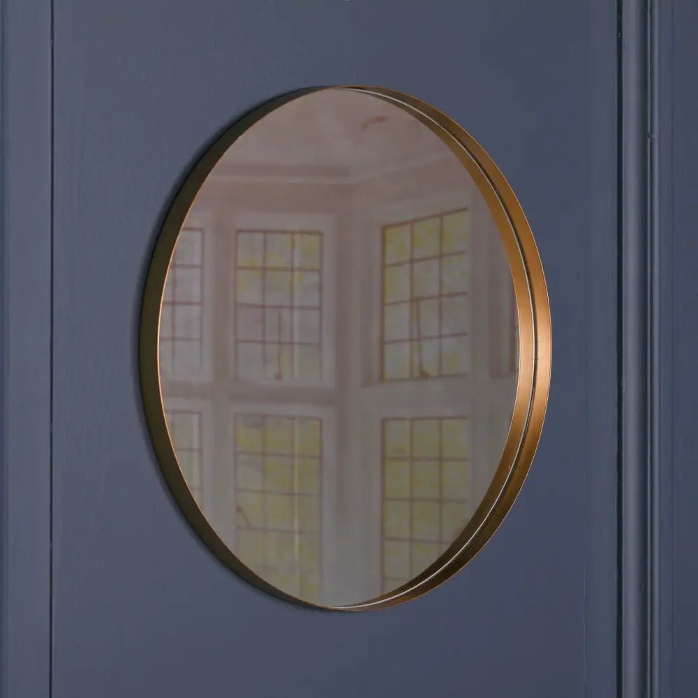 Circular gold-framed mirror reflecting window panes of Stylish 80cm Gold Round Wall Mirror