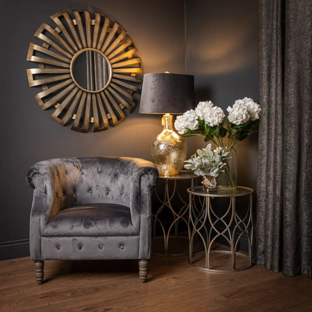 Gray velvet armchair with tufted upholstery and wooden legs near Evi Antique Silver Sunburst Mirror