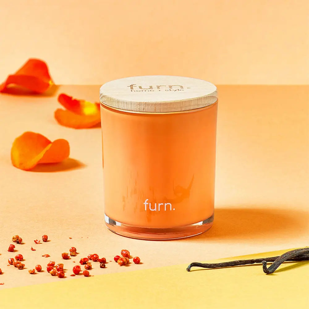 Orange cylindrical candle jar labeled furn for Floral & Berry Patchouli Scented Glass Candle