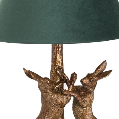 Antique gold marching table lamp with kissing hares and a stylish green velvet shade