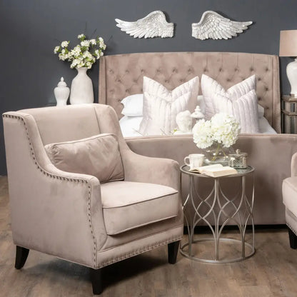 Elegant beige upholstered armchair beside antique silver horizontal angel wings decor